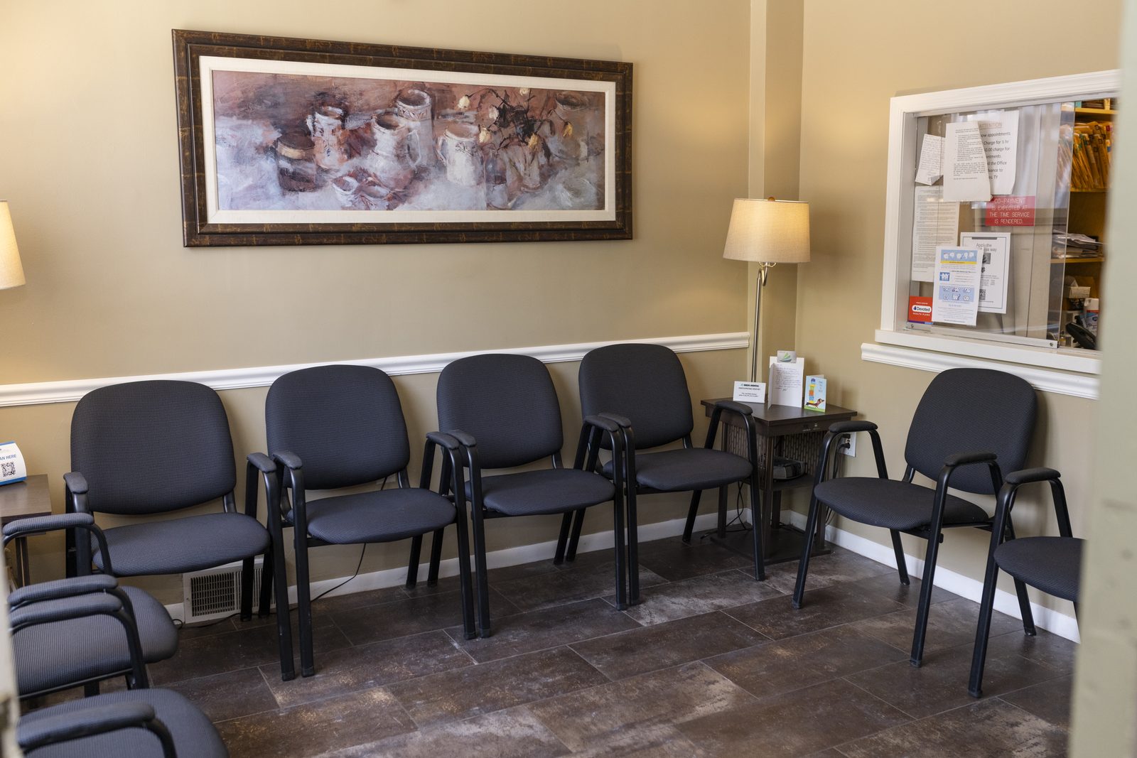 The waiting room, with seating along the wall and the reception window at right